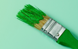a paintbrush with green paint on to represent green washing