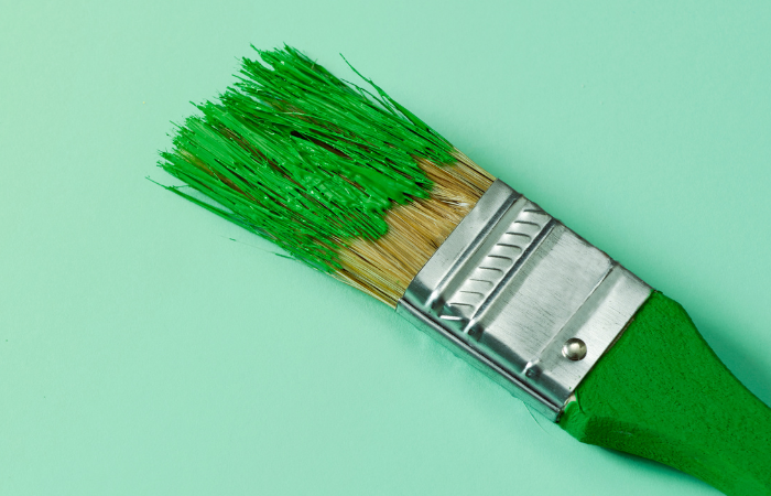 a paintbrush with green paint on to represent green washing